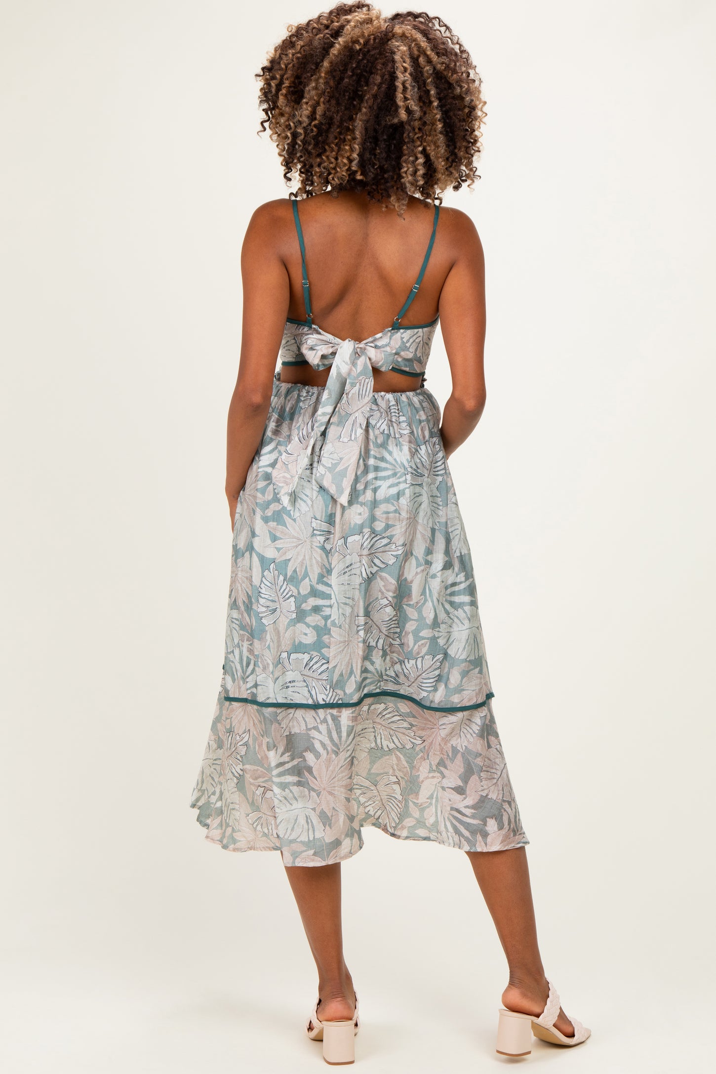 woman wearing a flowy light blue maternity dress with a botanical print and a tied back detail