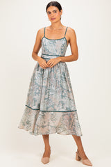 woman wearing a floral print midi dress with adjustable spaghetti straps and a flowing skirt, styled with nude heels