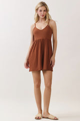 woman wearing a rust colored spaghetti strap dress with a flared skirt and sandals
