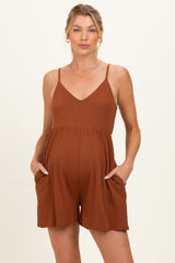 woman wearing a rust-colored sleeveless maternity romper with a v-neck and side pockets, showing her baby bump