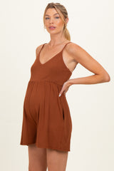 woman wearing a rust-colored maternity romper with adjustable straps and a relaxed fit, showcasing her baby bump