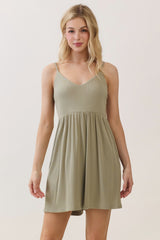 woman wearing a light olive green spaghetti strap mini dress with a fitted bodice and flared skirt