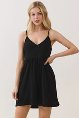 woman wearing a black spaghetti strap mini dress with a fitted bodice and flared skirt