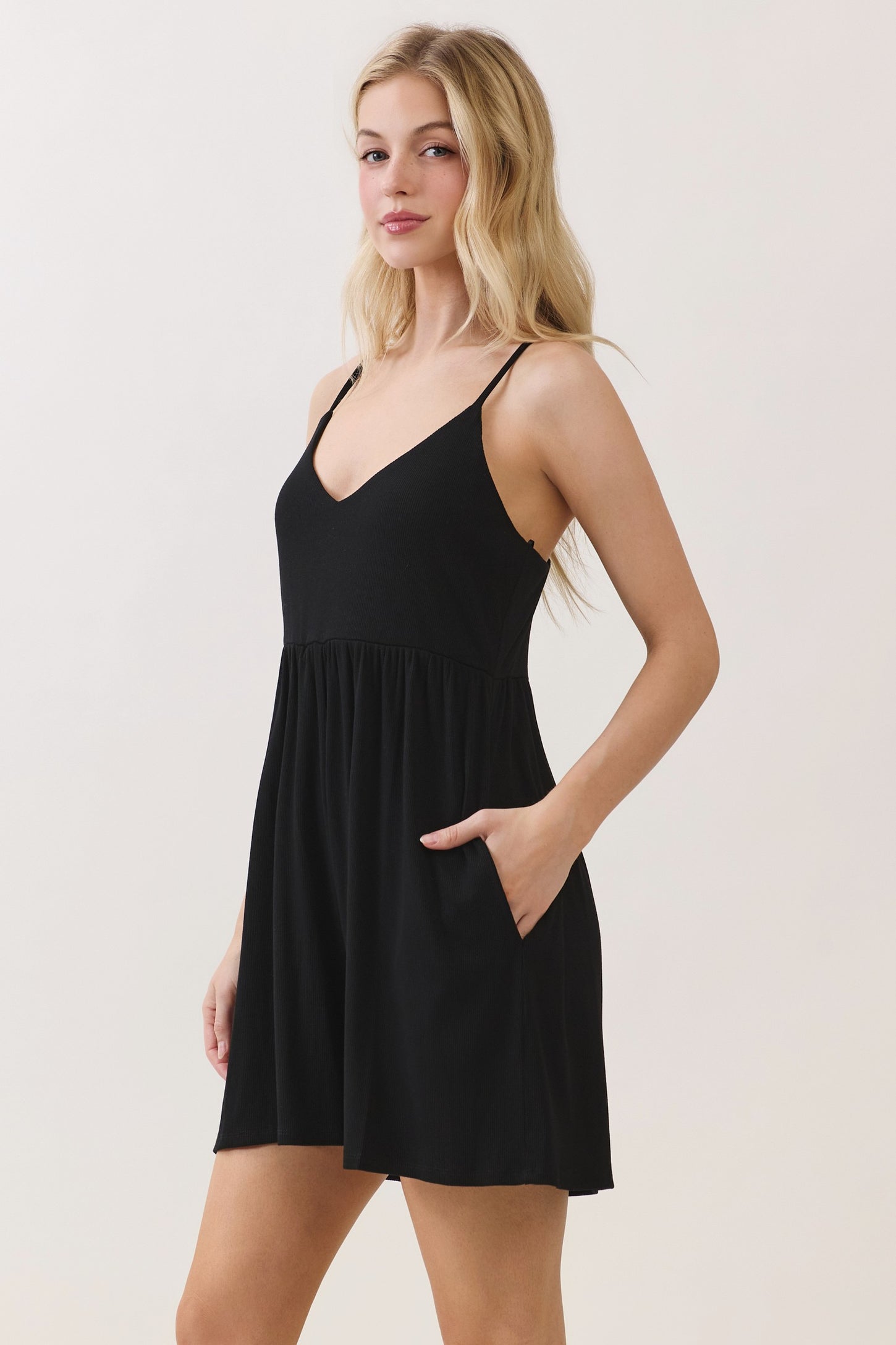 woman wearing a black sleeveless mini dress with a V-neck and pockets