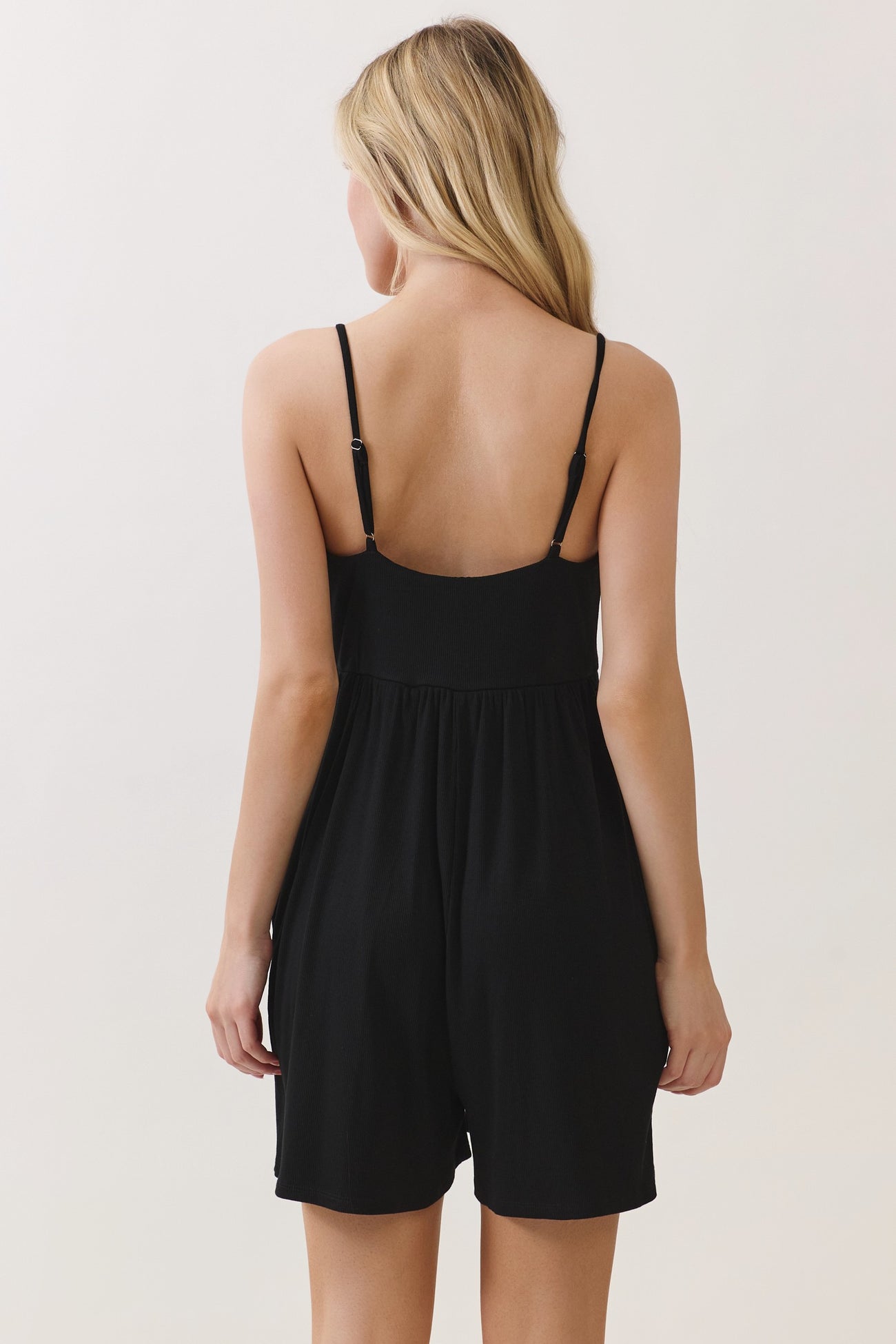 woman wearing a black sleeveless romper with a low back and loose fit