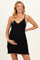 woman wearing a black maternity dress with a v-neckline and spaghetti straps, gently holding her baby bump