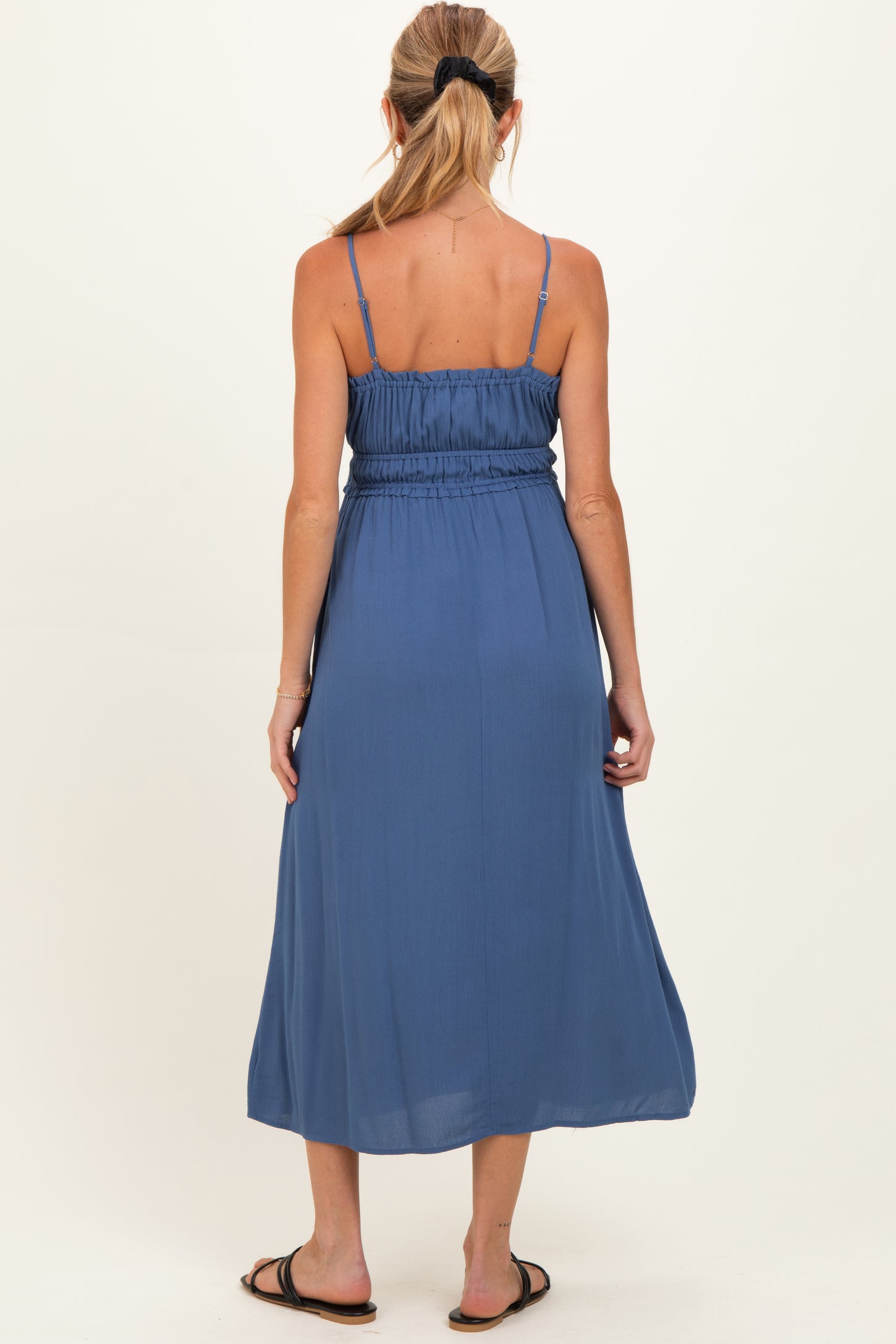 woman wearing a flowy navy blue maternity maxi dress with a smocked bodice and adjustable spaghetti straps