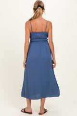 woman wearing a flowy navy blue maternity maxi dress with a smocked bodice and adjustable spaghetti straps