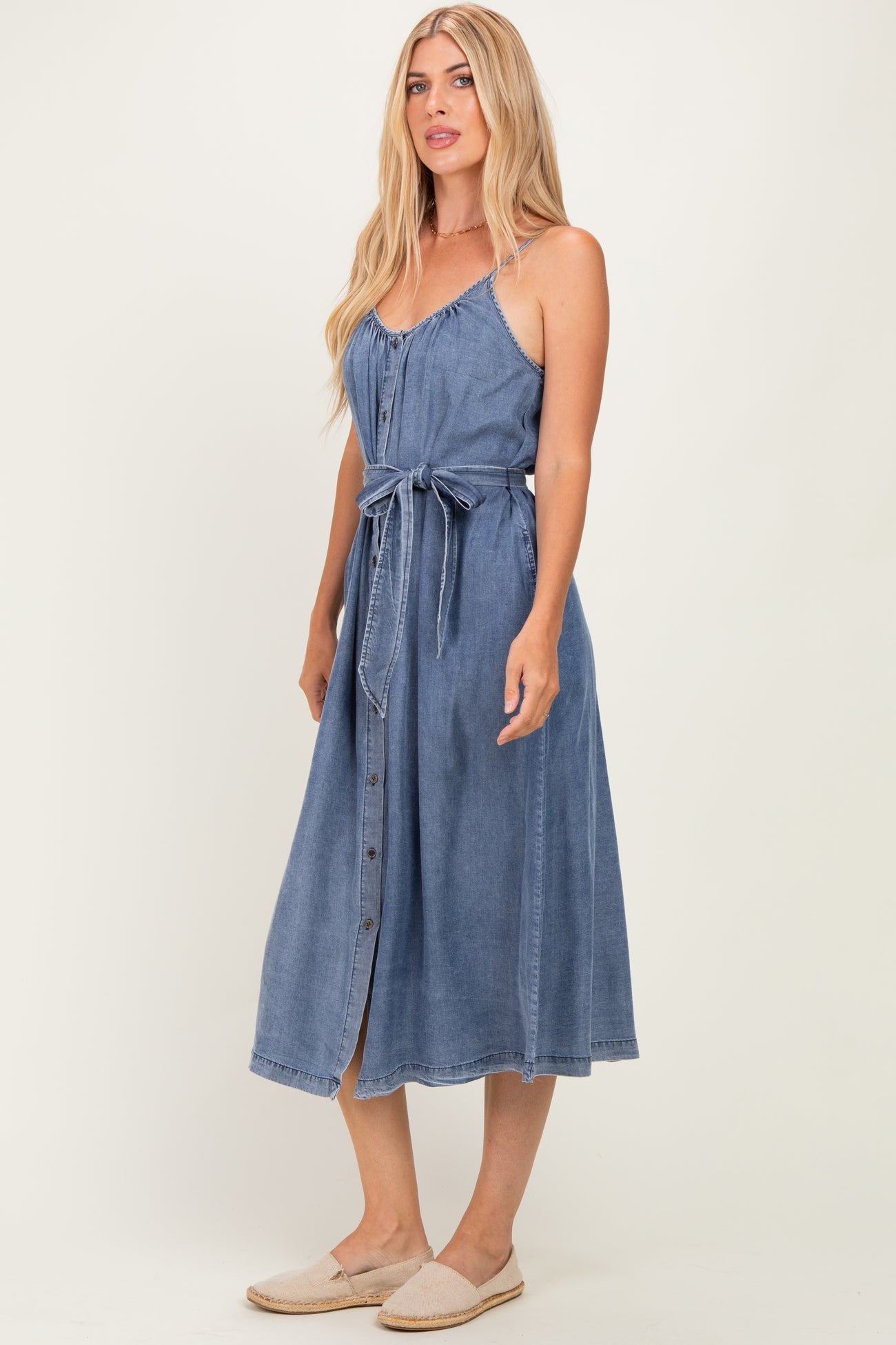 woman wearing a chambray button-up midi dress with a tie waist and thin straps