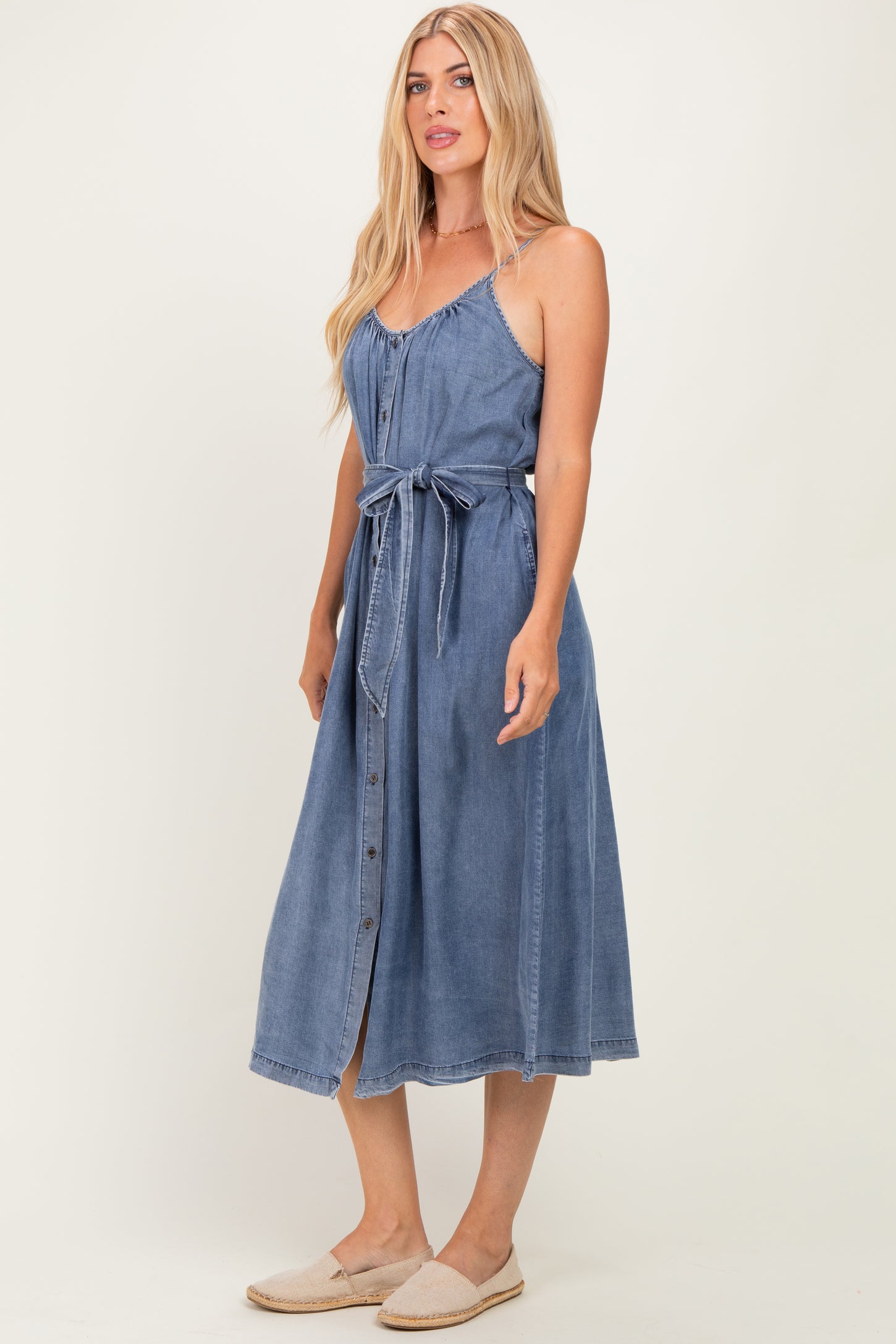woman wearing a chambray button-up midi dress with a tie waist and thin straps
