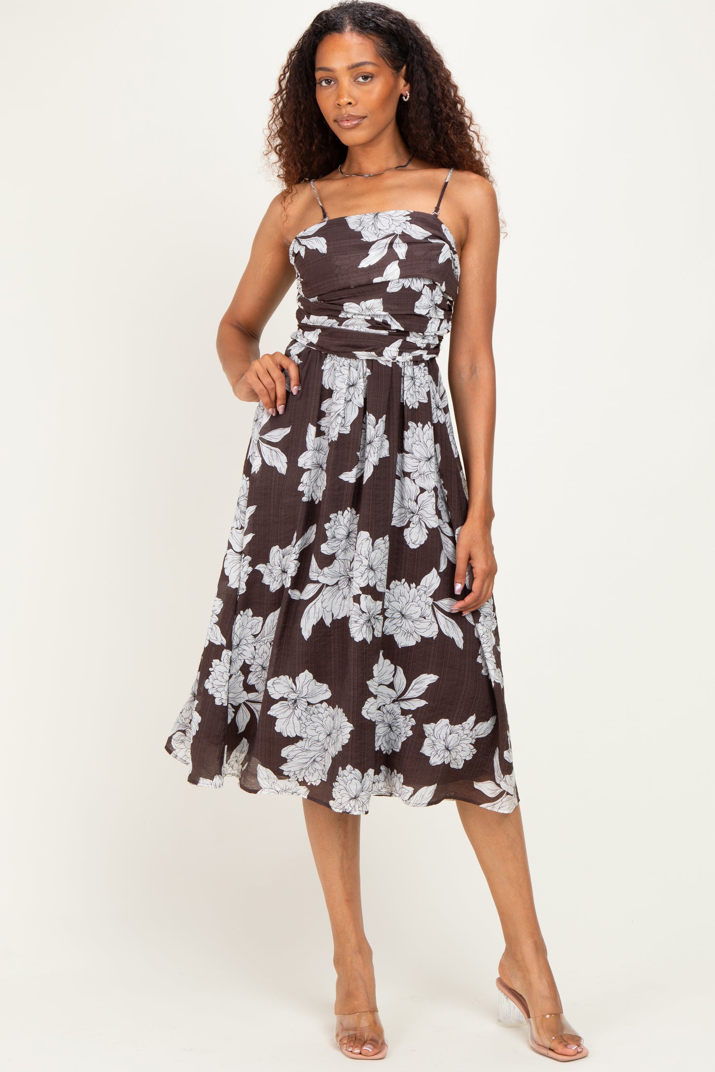 woman wearing a brown floral midi dress with spaghetti straps and a fitted bodice