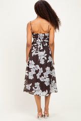 woman wearing a brown floral midi dress with a bow at the back and thin straps