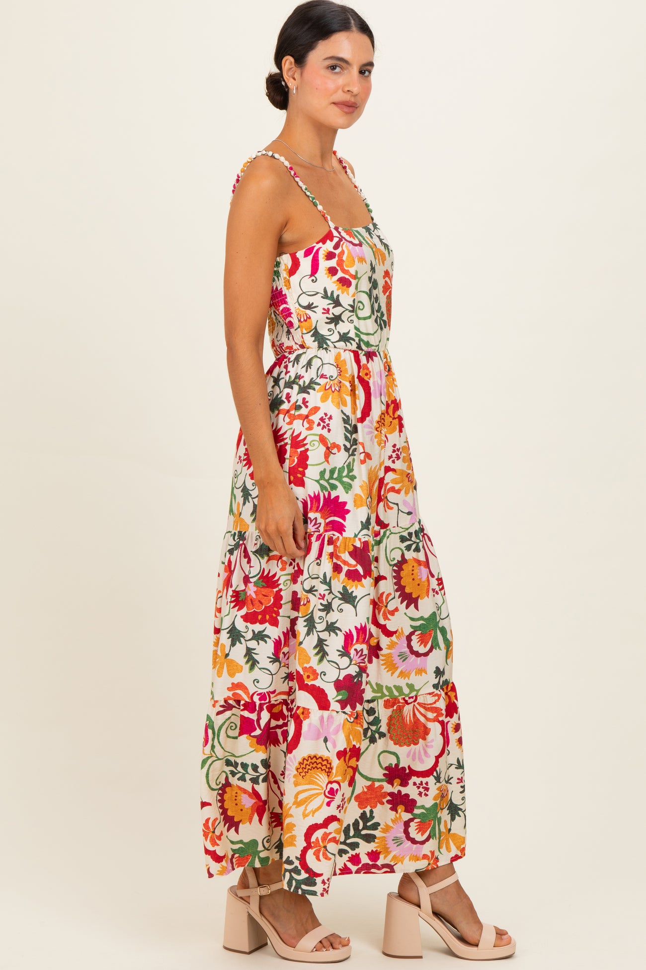 woman wearing a colorful floral maxi dress with adjustable straps and a fitted waist
