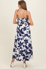 woman wearing a navy and white floral print maternity maxi dress with smocked back and adjustable straps