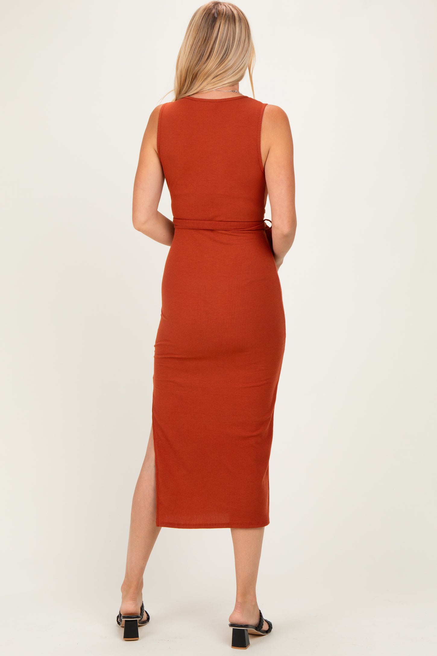 woman wearing a rust-colored sleeveless maxi dress with a side slit, shown from the back