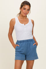 woman wearing a white button-up tank top and blue drawstring shorts with pockets and decorative stitching