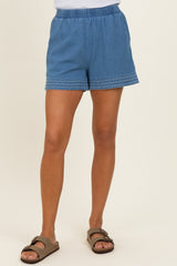 woman wearing light blue denim shorts with elastic waistband and decorative stitching at the hem