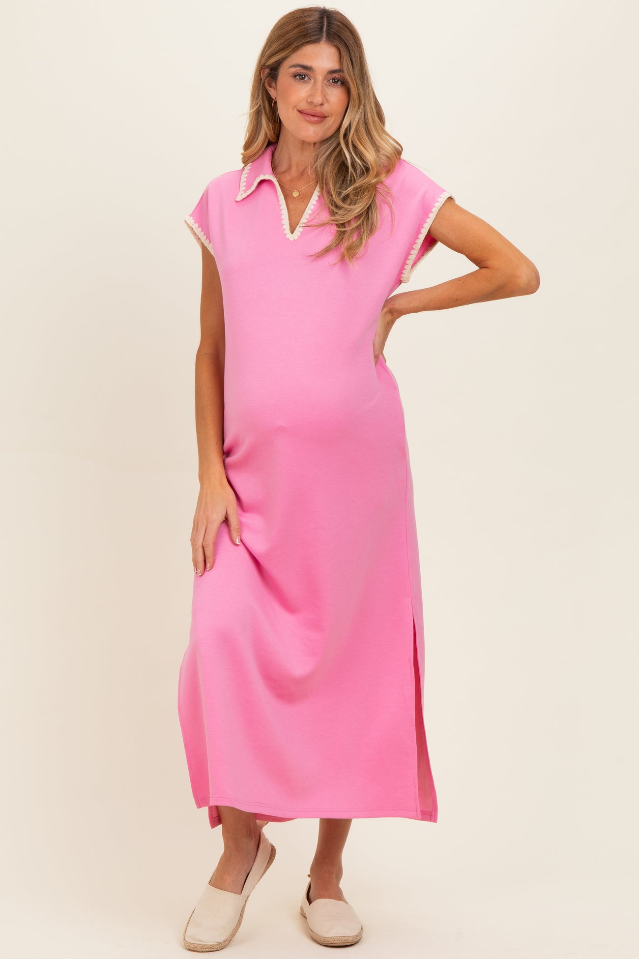 woman wearing a pink maternity dress with a collar and side slit, showcasing her baby bump
