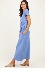 woman wearing a light blue maxi dress with short sleeves and a knot detail at the waist, paired with beige mules