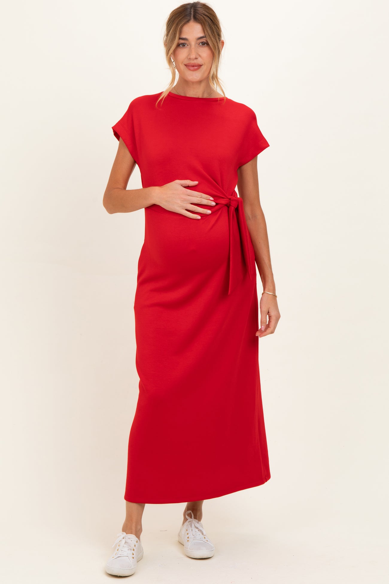 woman wearing a red short sleeve maternity maxi dress and holding her baby bump