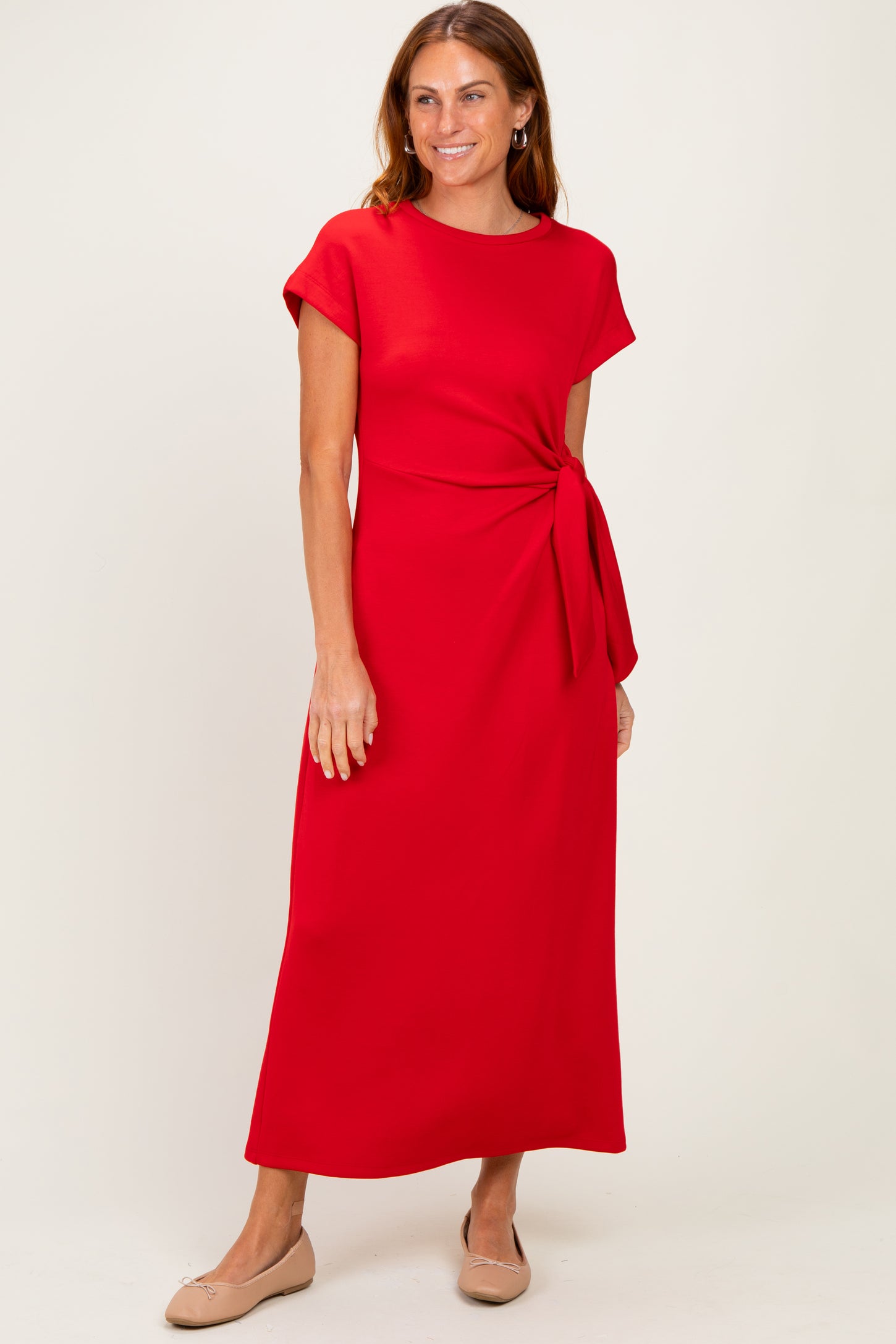 woman wearing a red short sleeve maxi dress with a knotted waist detail and beige flats