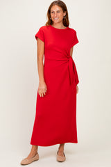 woman wearing a red short sleeve maxi dress with a knotted waist detail and beige flats