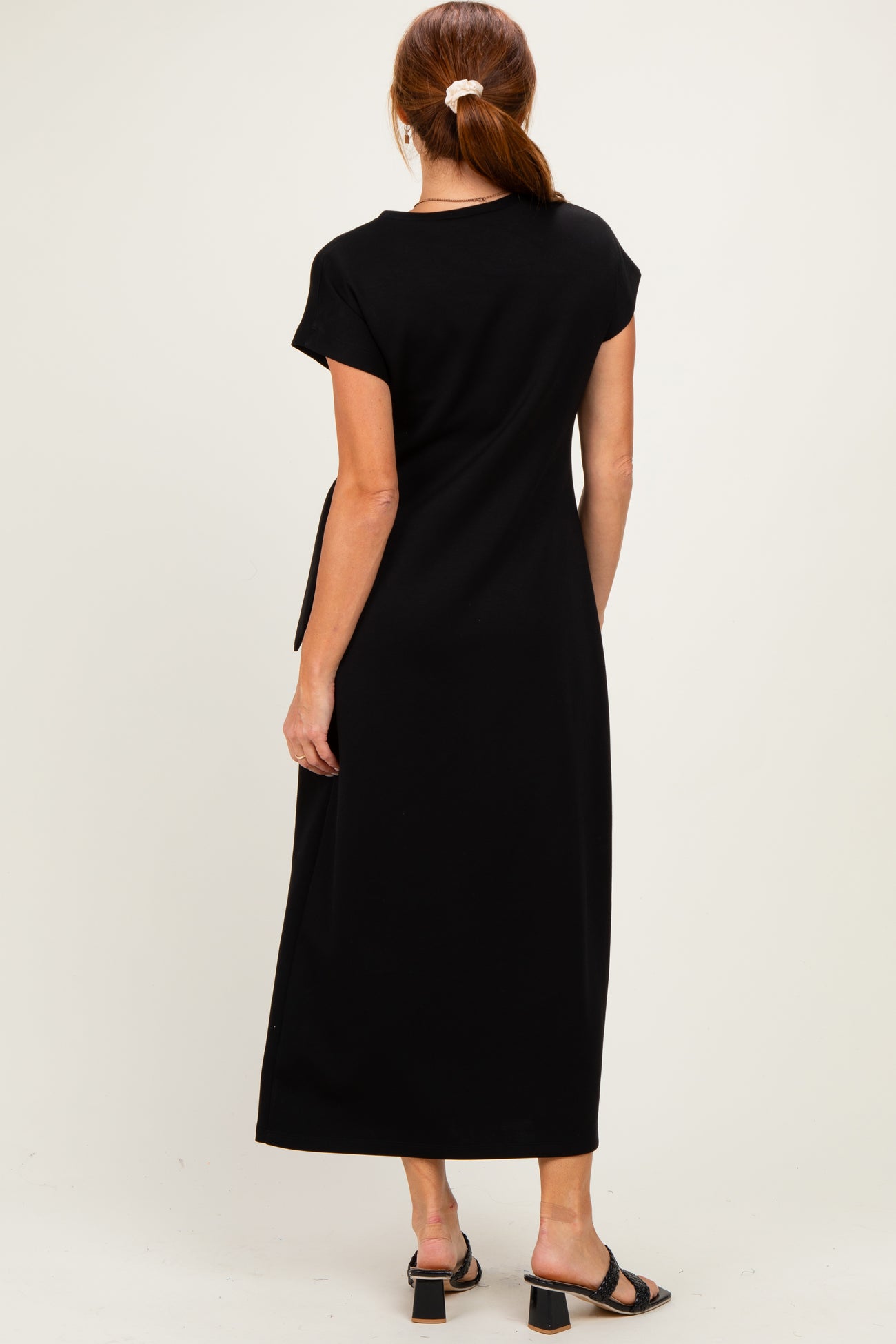 woman wearing a black maxi dress with short sleeves and a relaxed fit, seen from the back
