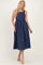 woman wearing a navy blue polka dot midi dress with adjustable straps and pockets