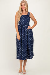 woman wearing a navy blue polka dot midi dress with a square neckline and adjustable straps