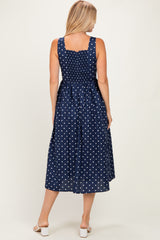woman wearing a navy blue polka dot sundress with a smocked back and a midi length, showing the back view