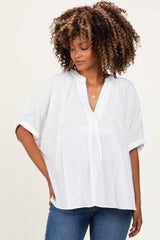 woman wearing a white maternity top with a v-neck and short sleeves, styled with denim jeans