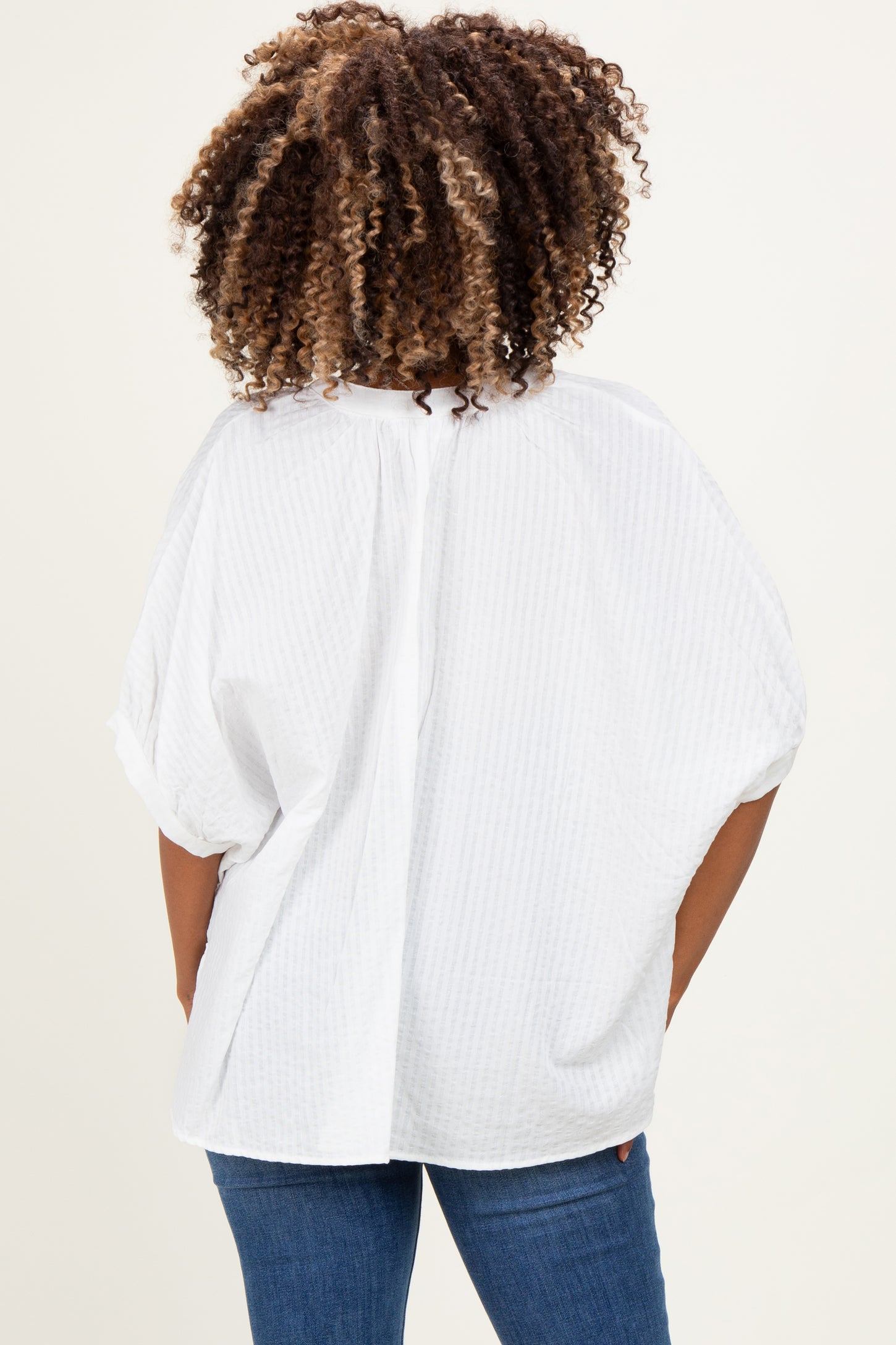 woman wearing a white short sleeve maternity top with a loose fit and a pleated back, viewed from the back