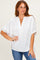 woman wearing a white short sleeve blouse with a v-neck and loose fit paired with blue jeans