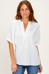 woman wearing a white short sleeve textured blouse with a v-neck and rolled sleeves