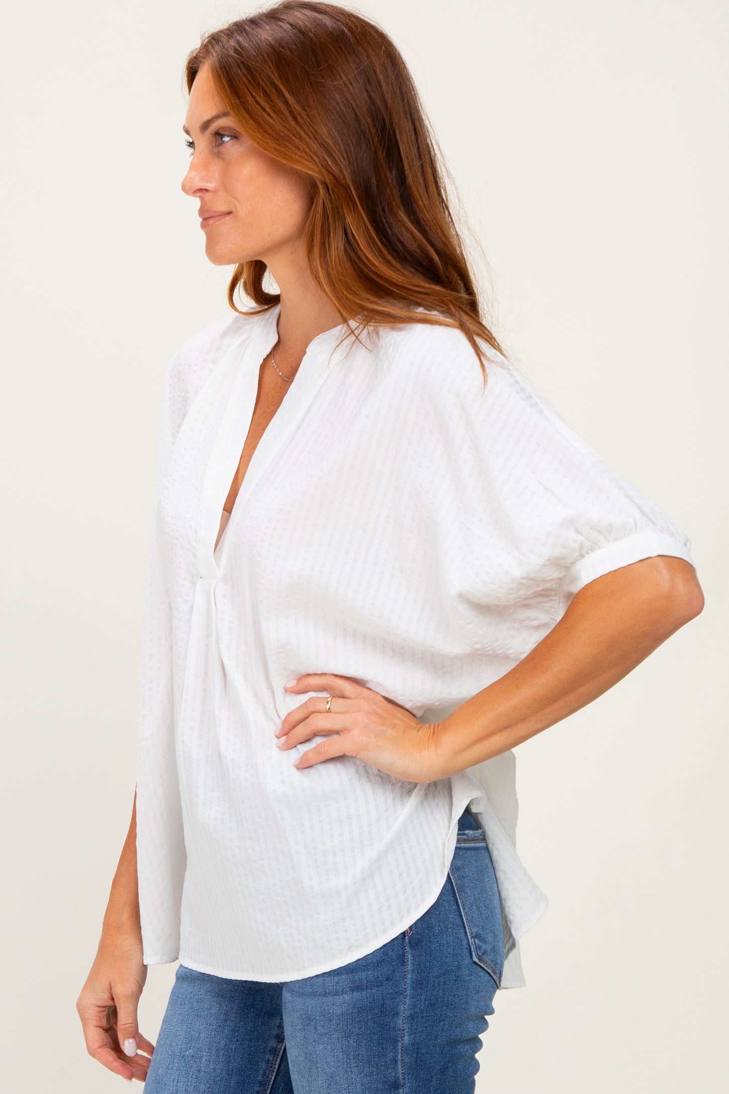 woman wearing a white short sleeve blouse with a v-neck and relaxed fit paired with blue jeans