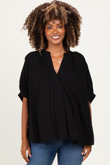 woman wearing a black maternity top with a relaxed fit and short sleeves, smiling at the camera