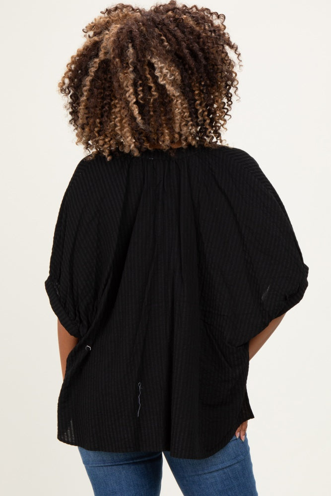 woman wearing a black maternity top with a textured pattern and puff sleeves, shown from the back