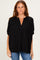 woman wearing a black loose-fit striped blouse with a v-neck and short sleeves, paired with blue jeans
