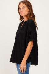 woman wearing a black textured short sleeve top with a relaxed fit and a front placket, paired with blue jeans