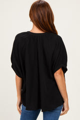 woman wearing a black short sleeve top with a textured pattern and relaxed fit, showing the back view