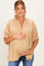 woman wearing a tan short sleeve maternity top with a relaxed fit and holding her baby bump