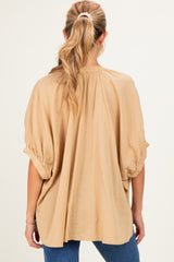 woman wearing a beige maternity top with a loose fit and puffed short sleeves, seen from the back