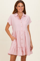 woman wearing a light pink maternity button-up dress with short sleeves and a tiered ruffle hem