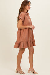 woman wearing a rust-colored short sleeve button-up dress with a ruffled hem and sandals