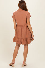 woman wearing a rust colored short sleeve dress with a tiered ruffle hem and sandals, shown from the back