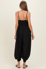 woman wearing a black maternity jumpsuit with a smocked back and loose, tapered legs