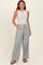 woman wearing a sleeveless light gray top and blue striped wide-leg pants with pockets