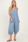 woman wearing a light blue denim jumpsuit with a button detail and balloon-style legs, styled with flip-flops