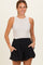 woman wearing a beige sleeveless top and black maternity shorts with pockets
