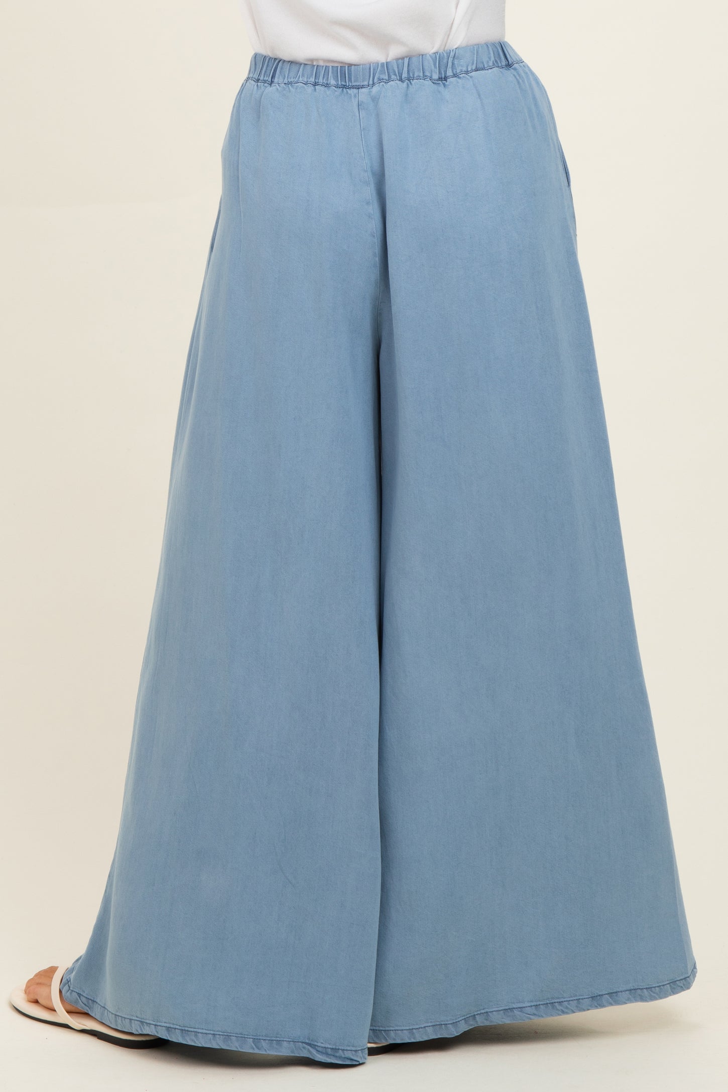 woman wearing light blue wide-leg pants with an elastic waistband, viewed from the back